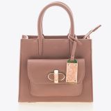 A small, blush pink leather handbag with top handles, a front pocket with a gold clasp, and a decorative pink marble luggage tag attached to one handle, set against a plain white background.