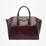 A stylish handbag with dark brown handles and sides, featuring a textured, burgundy reptile-skin pattern on the front and center, set against a plain white background.
