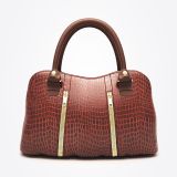 A brown, crocodile-patterned leather handbag with two sturdy handles and two vertical gold zippers on the front, displayed against a plain white background.