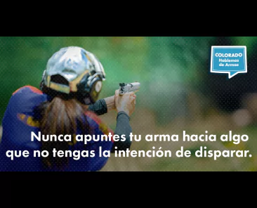 Una persona con protección para los oídos y los ojos apunta con una pistola a un blanco al aire libre. El texto en español dice: "Nunca apuntes tu arma hacia algo que no tengas la intención de disparar".